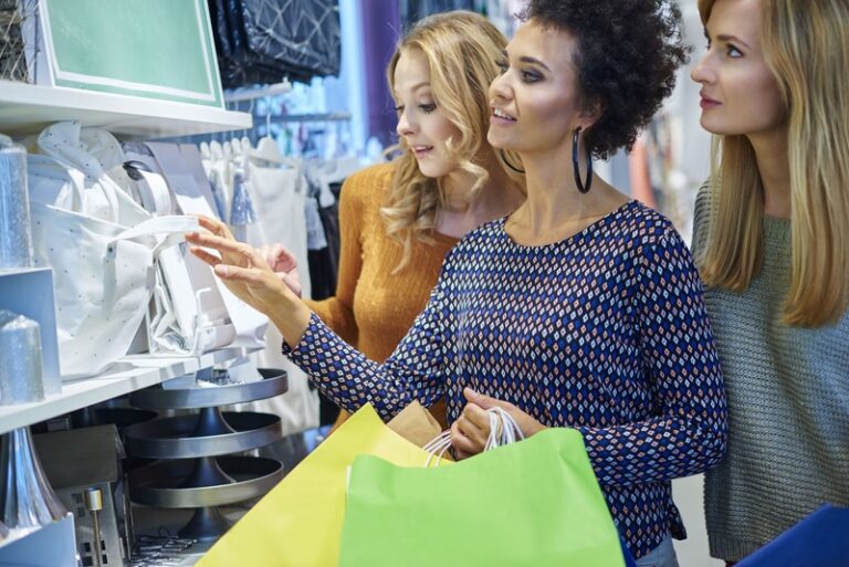 Mulheres veem vitrine de loja ouvindo música
